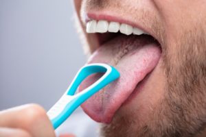 Closeup of man demonstrating how to clean your tongue