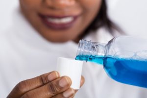 Closeup of smiling woman using mouthwash