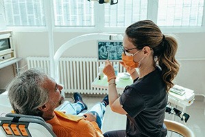 Smiling dental assistant reviewing X-ray with patient