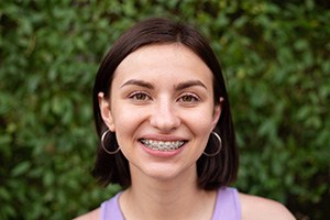 Young woman in purple shirt smiling with braces