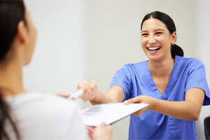 Dentist with purple gloves placing clear aligner on patient's teeth