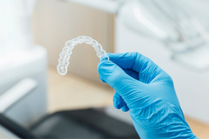 Dentist holding clear aligner with blue glove