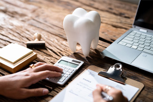Patient calculating cost of Invisalign on desk with office supplies