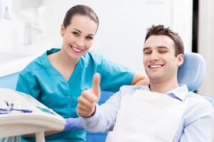 a person visiting their dentist and giving a thumbs-up