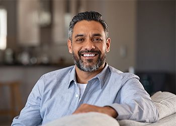 Man in blue shirt smiling on couch