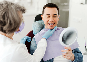 Man smiling at reflection in mirror with dentist